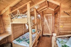 a bedroom with two bunk beds in a log cabin at Treehouse Křemílek in Jesenice
