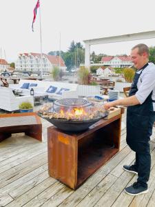 Un uomo che cucina cibo su un barbecue su un ponte di Hummeren Hotel a Tananger