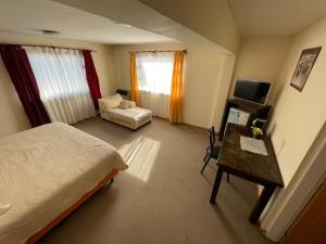 a bedroom with a bed and a desk and a television at Hosteria Lago Cardiel in Gobernador Gregores