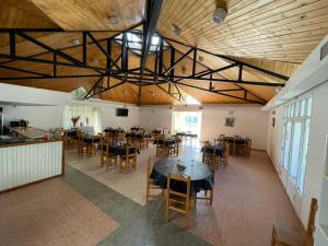 una sala da pranzo con tavoli, sedie e soffitto di Hosteria Lago Cardiel a Gobernador Gregores