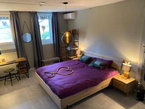 a bedroom with a large purple bed and a desk at Gasthuys de Peel in Ospel