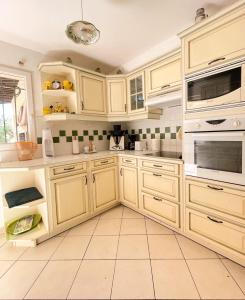 a kitchen with wooden cabinets and a tile floor at villa for 10 people with private pool 250m from the sea in Saint-Aygulf