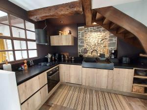 a kitchen with black countertops and a stone wall at Maison de contes en amoureux in Taden