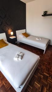 2 camas en una habitación con sábanas blancas y toallas en Da Vinci's House, a due passi dalla Reggia, en Venaria Reale