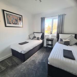 a bedroom with two beds and a window at Levenside Holiday Apartment, Balloch, Loch Lomond in Balloch