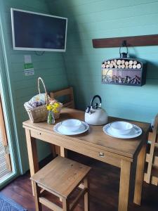 a wooden table with two plates and a tea kettle on it at Ty Cnocell in Boncath