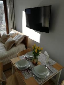 einen Esstisch mit 2 Tellern und einen TV in der Unterkunft Apartament Ami Stegna in Stegna