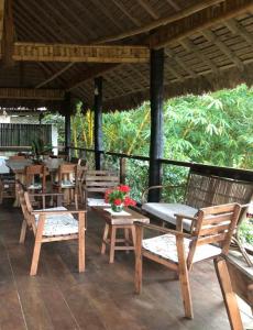 a patio with wooden chairs and tables and a roof at Casa de Campo in Rurrenabaque