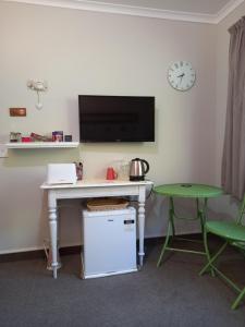 a desk with a tv and a table with a chair at b&b @ fynnz in Turangi