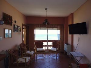 een woonkamer met stoelen, een televisie en een raam bij Departamento BellaVista in Puerto Madryn