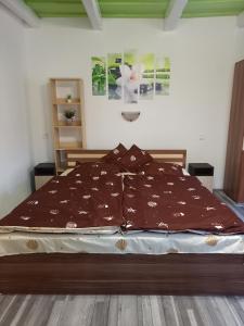 Una cama con un edredón marrón encima. en Sweet Home Apartman Szilvásvárad en Szilvásvárad