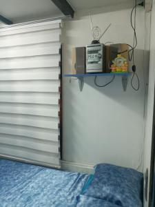 a bedroom with a bed and a microwave on a shelf at Terminal Pajarito in Santiago