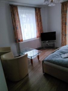 - un salon avec un lit, une table et une télévision dans l'établissement Pension Insulaner, à Brême