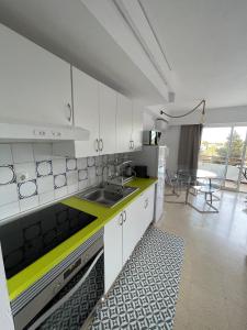 cocina con armarios blancos y encimera amarilla en Cosy studio with pool, en Puerto de Alcudia