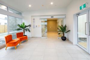 an empty lobby of a hospital with two orange chairs at Copthorne Hotel Greymouth in Greymouth