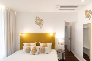 um quarto com uma cama branca e uma cabeceira amarela em Apartamento Avenida em Viana do Castelo