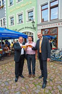 un groupe de trois hommes tenant une assiette alimentaire dans l'établissement Schwerter Schankhaus & Hotel, à Meissen