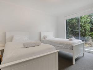 2 łóżka w białej sypialni z oknem w obiekcie The White House Merimbula w mieście Merimbula