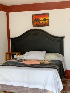 a bed with a black headboard in a bedroom at Hotel Villa del Lago, Gladys in San Pedro La Laguna