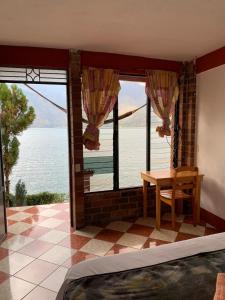 Schlafzimmer mit einem Tisch und Blick auf das Wasser in der Unterkunft Hotel Villa del Lago, Gladys in San Pedro La Laguna