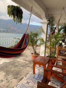 a hammock on a patio with a view of the water at Hotel Villa del Lago, Gladys in San Pedro La Laguna