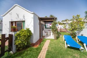 a white house with a yard with two blue chairs at Casa Tango in Puerto del Carmen