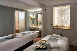 2 łóżka w pokoju hotelowym z lustrem w obiekcie Shangri-La Paris w Paryżu