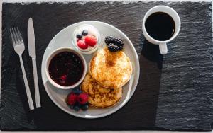 a plate with pancakes and berries and a cup of coffee at Best Western Plus Oslo Airport in Gardermoen