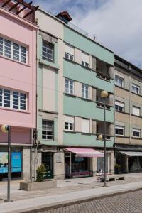 um edifício rosa e verde numa rua da cidade em Apartamento Avenida em Viana do Castelo