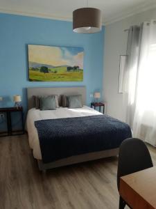 ein Schlafzimmer mit einem großen Bett mit blauer Wand in der Unterkunft Casa Fisher in Vendas Novas