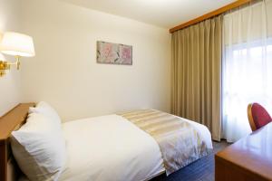 a hotel room with a bed and a desk and a window at Hotel Wakamizu in Takarazuka