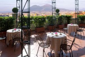 balcón con mesas y sillas y vistas a la ciudad en Starhotels Terminus en Nápoles