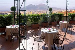 a balcony with tables and chairs and a view of the city at Starhotels Terminus in Naples