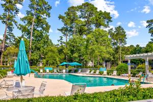 a swimming pool with chairs and a blue umbrella at Tidewater Condos in North Myrtle Beach