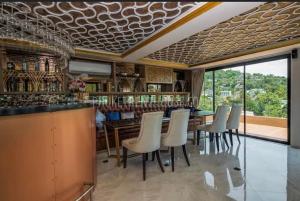 a dining room with a bar with white chairs at Phuket apartment surin beach in Thalang
