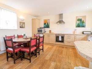 a kitchen with a wooden table and red chairs at Gratton Grange Farm- The Cottage in Bakewell