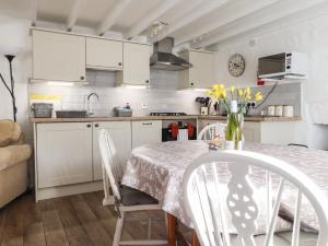 eine Küche mit weißen Schränken und einem Tisch und Stühlen in der Unterkunft End Cottage in Newport