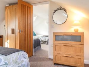 ein Schlafzimmer mit einem TV und einer Kommode mit einem Spiegel in der Unterkunft End Cottage in Newport