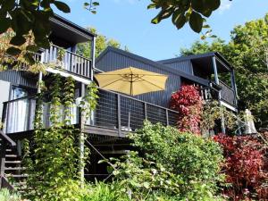 una casa negra con un paraguas amarillo delante de ella en Cloudsong Chalet 3 Close to the village centre en Kangaroo Valley