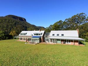 a large house on a field with a hill in the background at Yeola Lush location with river access in Upper Kangaroo River