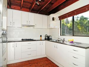 a white kitchen with white cabinets and a window at Sweet Gum Bend Delightful 2 bedroom cottage in Kangaroo Valley