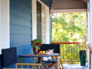a table on the front porch of a blue house at Peaceful Bushland Retreat in Kangaroo Valley