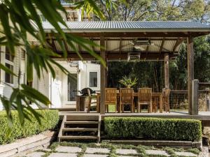 einen hölzernen Pavillon mit einem Tisch und Stühlen in der Unterkunft Equanimity Luxurious tranquil Kangaroo Valley home in Kangaroo Valley