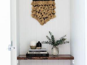 a shelf with books and a vase and a plant at Equanimity Luxurious tranquil Kangaroo Valley home in Kangaroo Valley