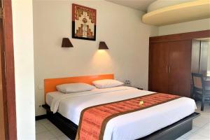 um quarto com uma cama grande e uma cabeceira laranja em The Yani Hotel Bali em Denpasar