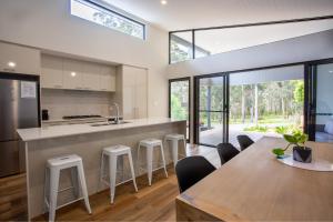 an open kitchen with a table and stools at Forest Getaway - walk to Margaret River town - NEW in Margaret River Town