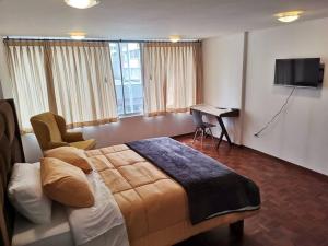 Dormitorio con cama, escritorio y TV en Suite Ejecutiva en Quito