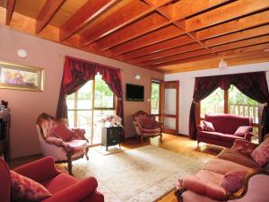 una sala de estar con sillas rojas y techo de madera. en Orange Blossom Retreat, en Valle Kangaroo