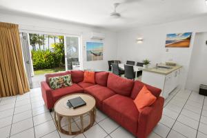 ein Wohnzimmer mit einem roten Sofa und einem Tisch in der Unterkunft Agincourt Beachfront Apartments in Clifton Beach