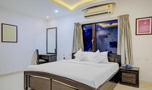 Un dormitorio con una gran cama blanca y una ventana en FabHotel Skyry en Chennai
